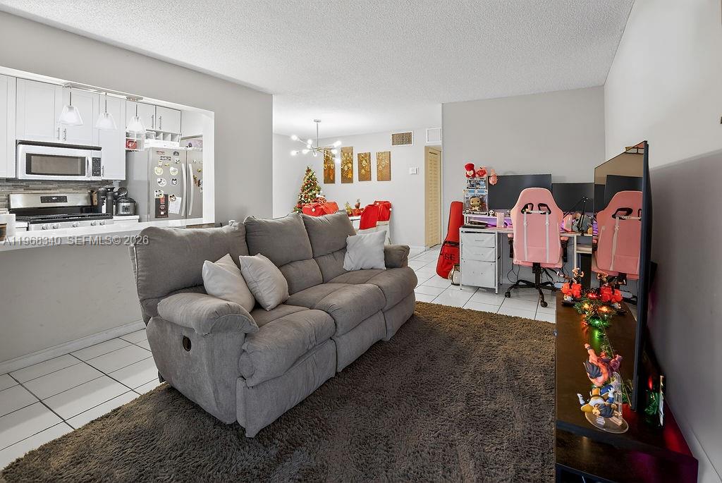 A living room features a grey sofa, a brown rug, and a desk with pink chairs — 20311 NE 2nd Ave # 15, Miami FL 33179, MIAMI, FL