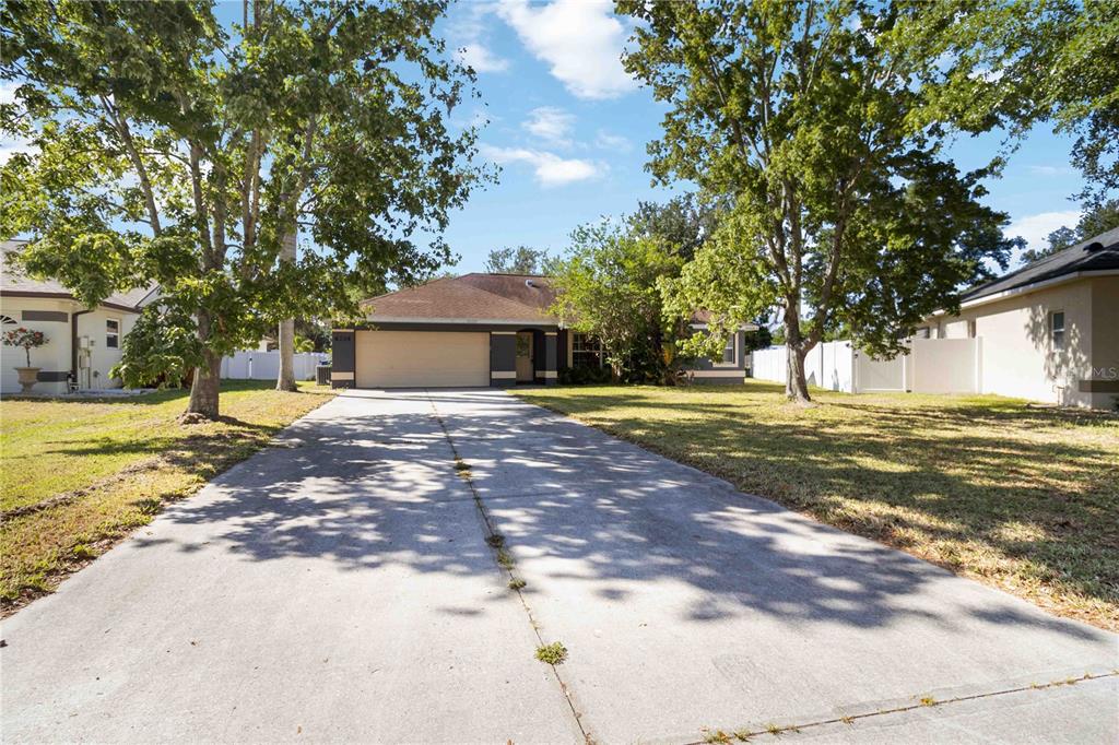 A single-story house with a concrete driveway and mature trees in the front yard — 6214 35TH AVENUE E, PALMETTO, FL