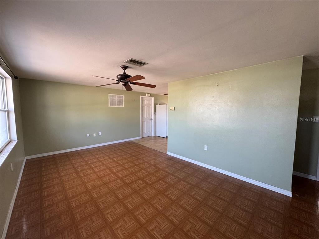 An empty room features light green walls, a ceiling fan, and brown parquet flooring — 1321 HONOR DRIVE, HOLIDAY, FL