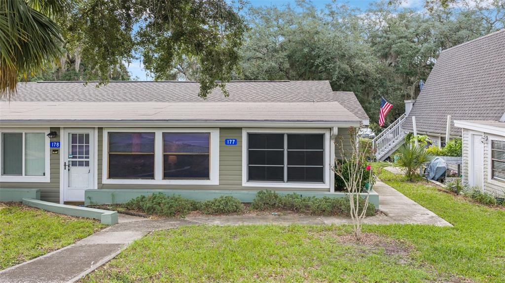 A single-story building with olive green siding, white trim, and a gray shingled roof — 10301 US HIGHWAY 27 UNIT 177, CLERMONT, FL