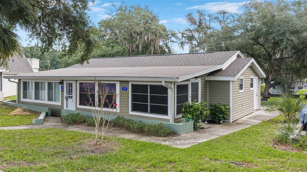 A single-story house with olive green siding, a screened-in porch, and a metal roof — 10301 US HIGHWAY 27 UNIT 177, CLERMONT, FL