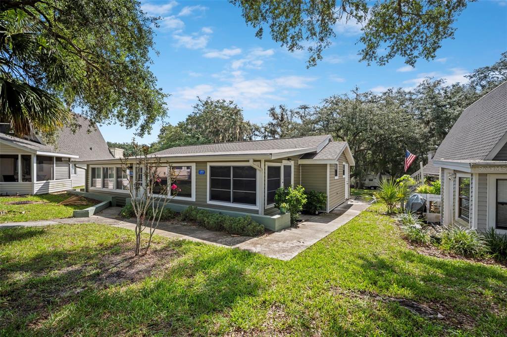 A single-story house with light green siding and a screened-in porch sits on a lawn — 10301 US HIGHWAY 27 UNIT 177, CLERMONT, FL