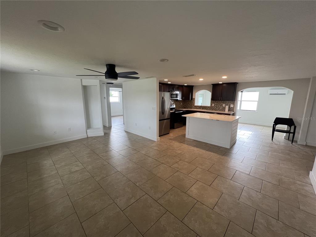 An open-concept kitchen and living area features tile flooring, a center island, and dark cabinetry — 5270 CITADEL ROAD, VENICE, FL