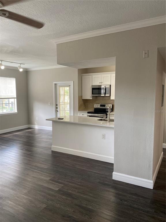 A kitchen with white cabinets and a breakfast bar opens into a living area — 2558 ROBERT TRENT JONES DRIVE UNIT 1424, ORLANDO, FL