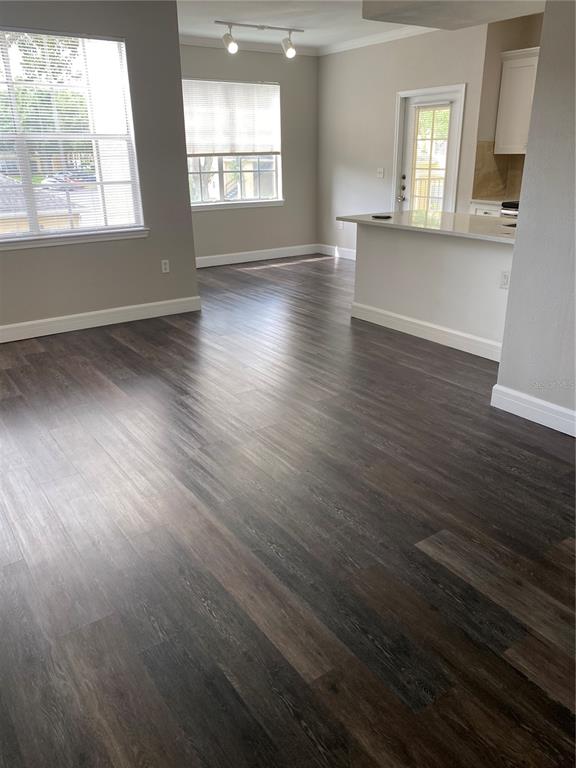 An open-concept living area features dark wood-look flooring, neutral walls, and a kitchen breakfast bar — 2558 ROBERT TRENT JONES DRIVE UNIT 1424, ORLANDO, FL