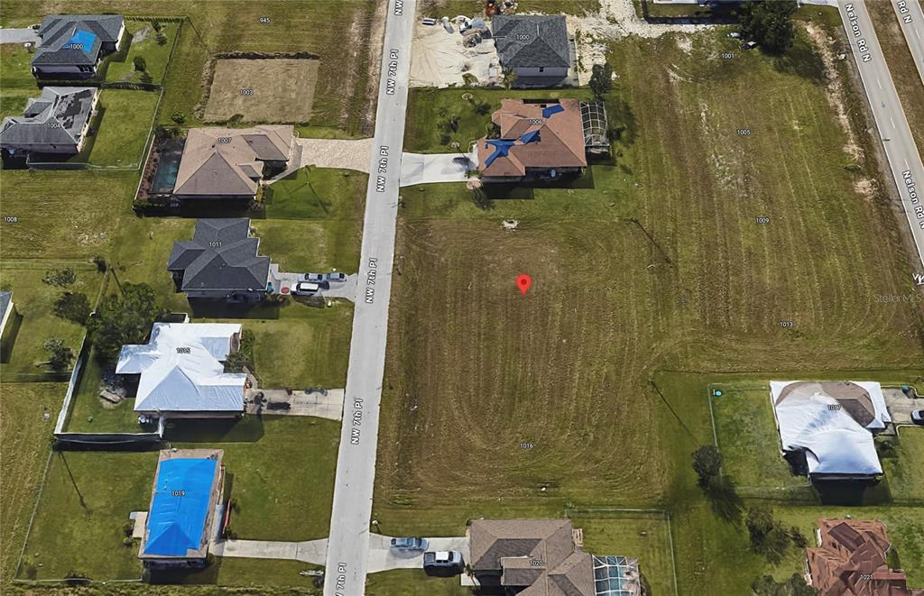 An aerial view shows a vacant, grass-covered residential lot marked with a red pin — 1012 NW 7TH PLACE, CAPE CORAL, FL