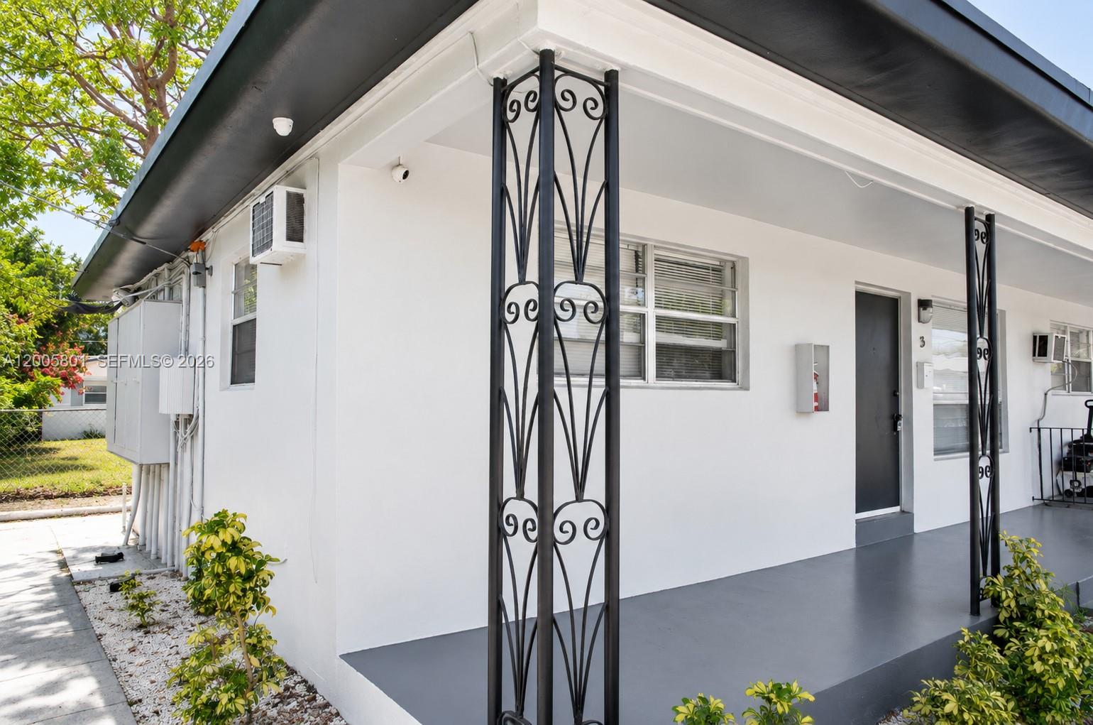 The exterior of a white building features a covered porch with decorative black metal columns — 2206 Fillmore St # 6, Hollywood FL 33020, HOLLYWOOD, FL