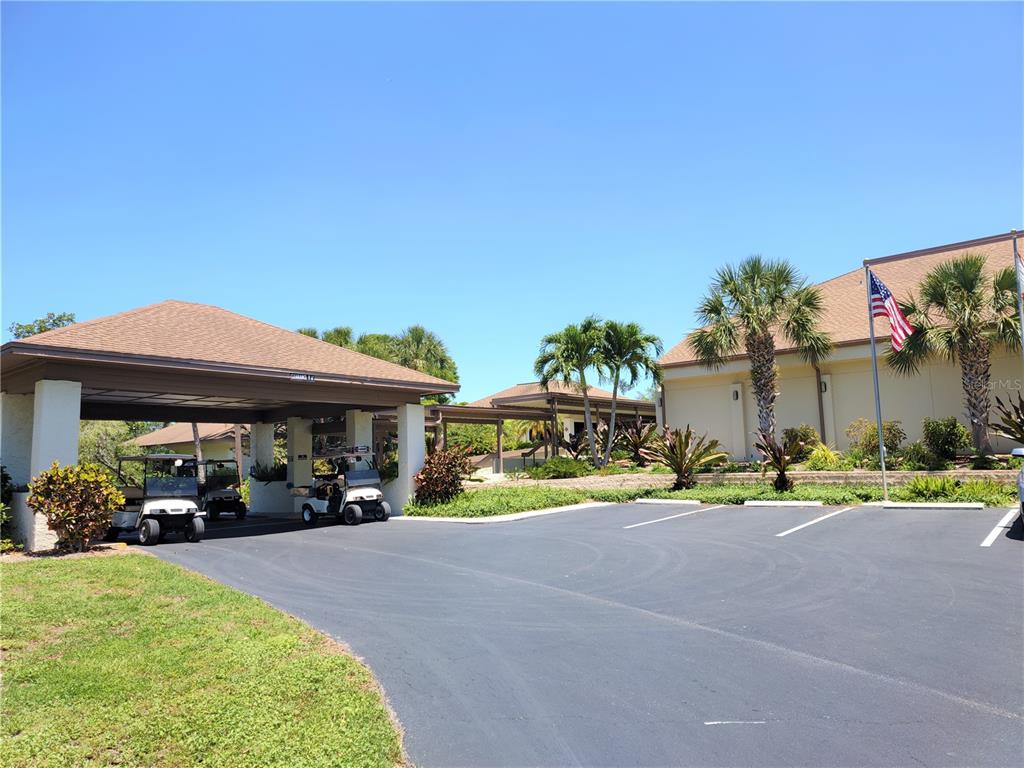 A paved driveway leads to a covered entrance with golf carts parked underneath — 650 BIRD BAY DRIVE E UNIT 105, VENICE, FL