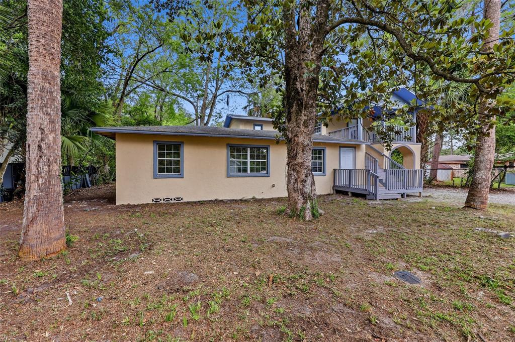 A two-story house with tan stucco siding, blue trim, and a wooden deck — 821 NE 22ND TERRACE, GAINESVILLE, FL