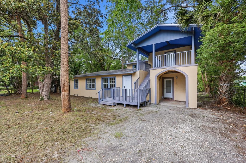 A two-story house with a gravel driveway, a wooden deck, and an exterior staircase — 821 NE 22ND TERRACE, GAINESVILLE, FL