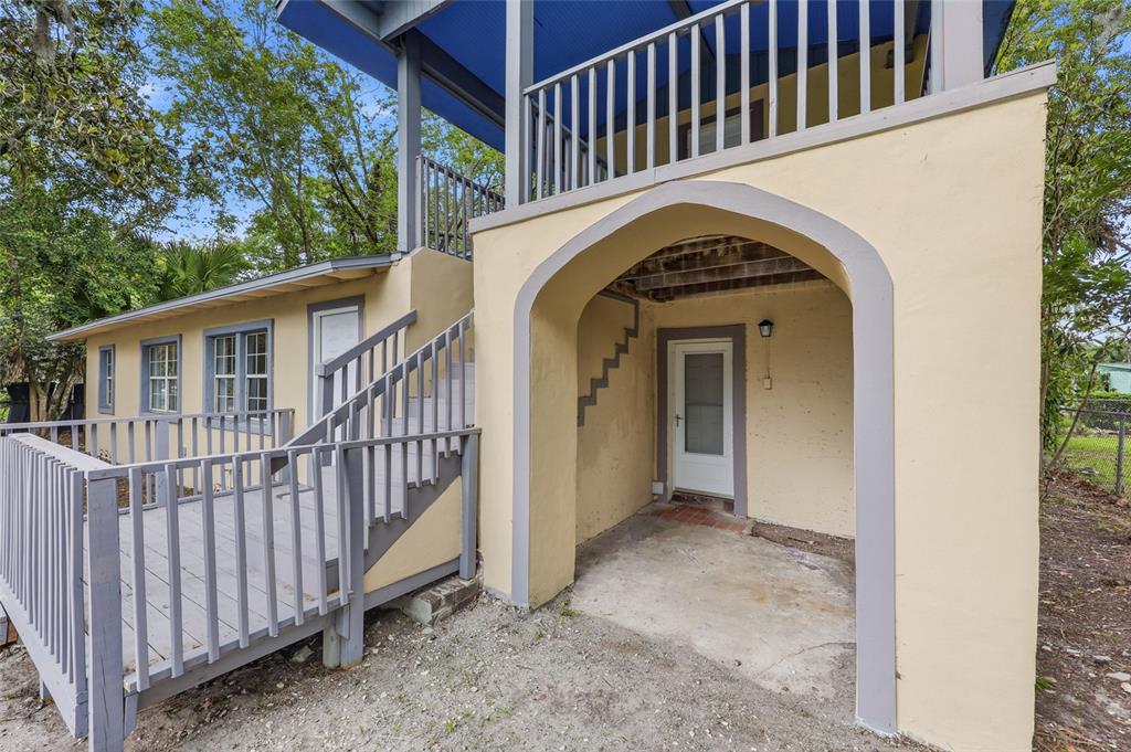 A two-story house exterior features a covered ground-level patio, a wooden deck, and stairs — 821 NE 22ND TERRACE, GAINESVILLE, FL