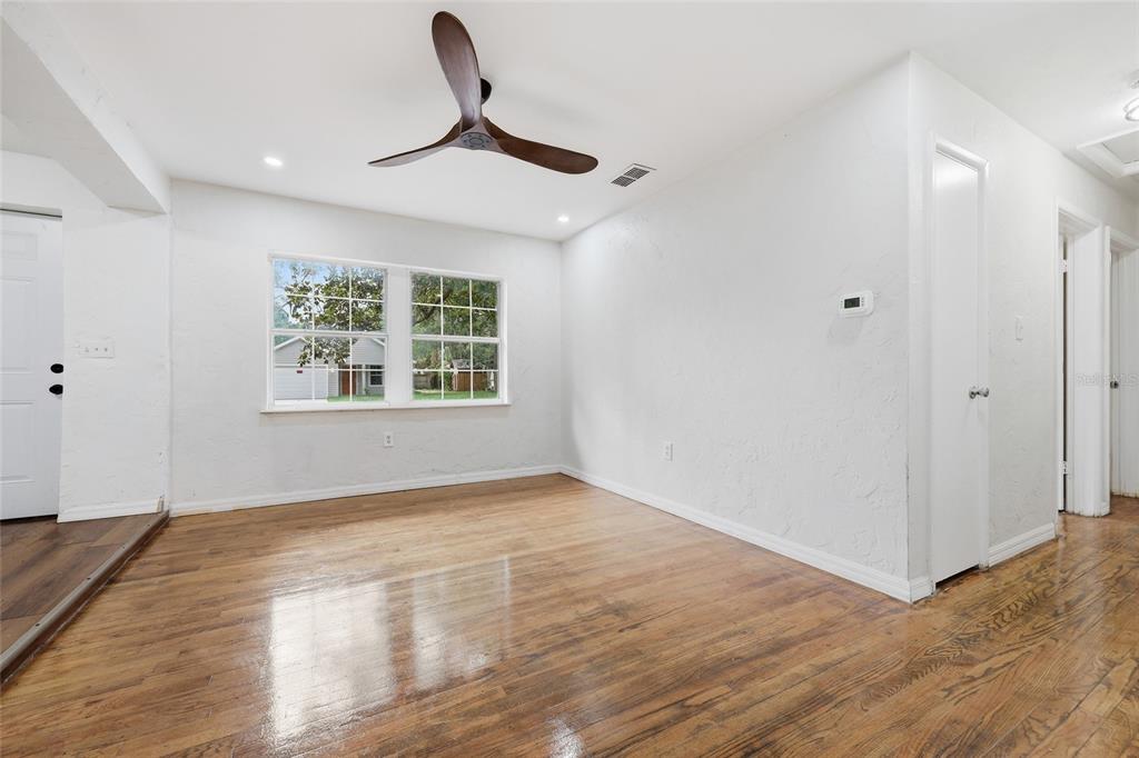 A room with white walls, hardwood floors, a ceiling fan, and a double window — 821 NE 22ND TERRACE, GAINESVILLE, FL