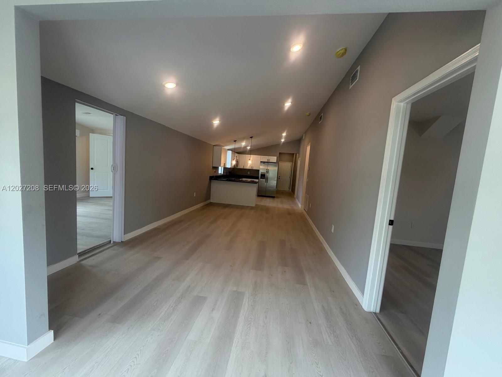 An open-concept living area features light wood-look flooring, gray walls, and a distant kitchen — 2331 Randall St, Sanford FL 32771, SANFORD, FL