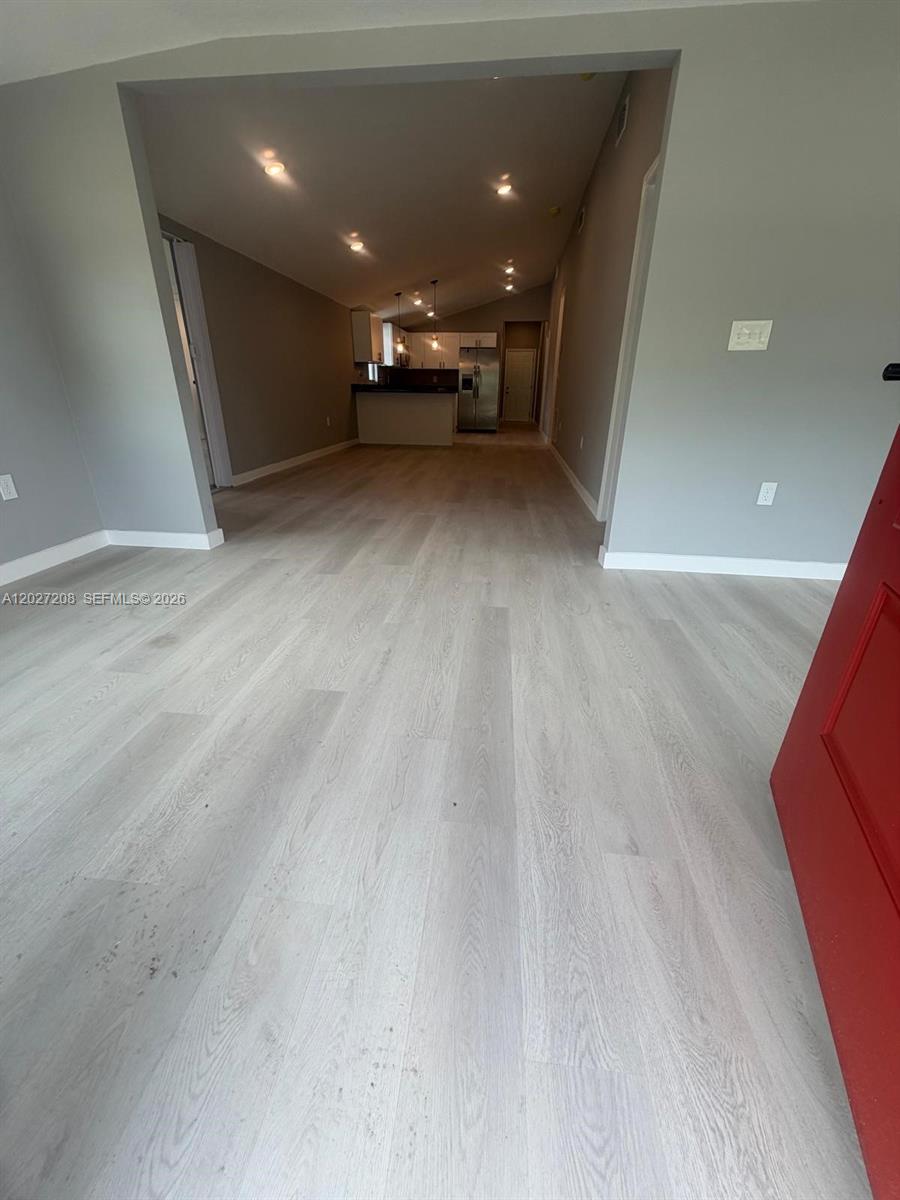 An open-concept living area features light-colored wood-look flooring and leads into a kitchen — 2331 Randall St, Sanford FL 32771, SANFORD, FL