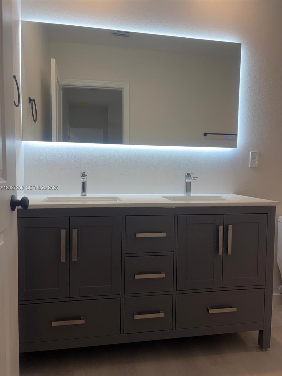 A bathroom features a double-sink vanity with gray cabinets and an illuminated rectangular mirror — 2331 Randall St, Sanford FL 32771, SANFORD, FL