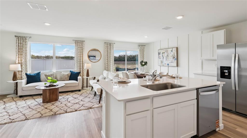 An open-concept kitchen and living area features white cabinetry, stainless appliances, and a dining space — 10141 SE 158TH LANE, SUMMERFIELD, FL
