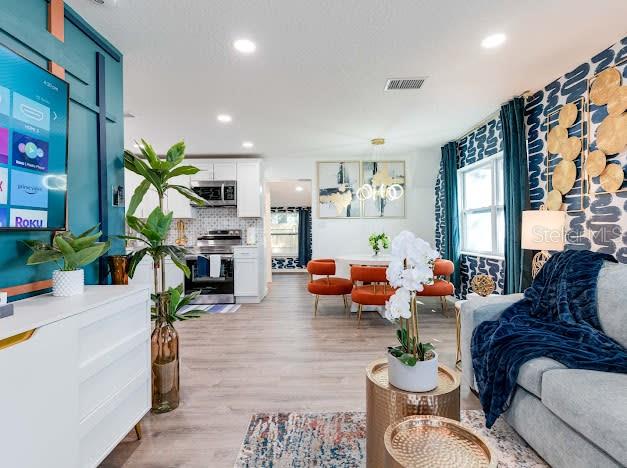 A dining room features a round table, orange chairs, and blue patterned wallpaper — 6225 76TH AVENUE N, PINELLAS PARK, FL