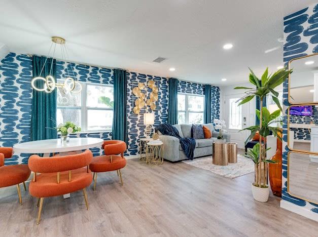 A bedroom features an orange accent wall with gold circular decor, a bed, and white furniture — 6225 76TH AVENUE N, PINELLAS PARK, FL