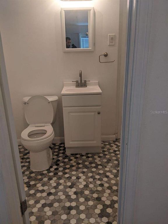 A small bathroom features a white vanity, a toilet, and a hexagonal tile floor — 729 VIRGINIA AVENUE, AUBURNDALE, FL