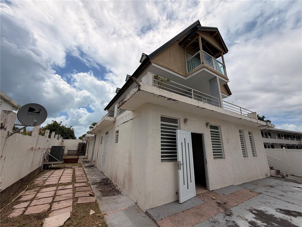A multi-story white stucco building features a top-floor balcony and a side patio area — Calle E E UNIT 190, DORADO, PR
