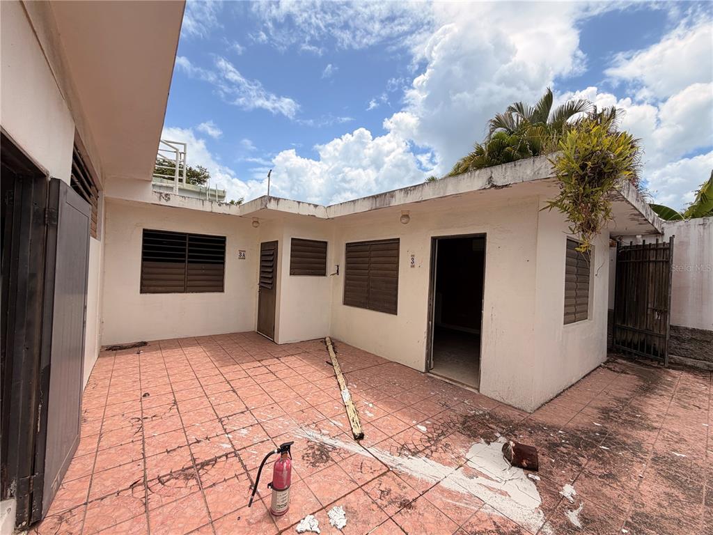 An exterior view of a building with a tiled patio, two doorways, and louvered windows — Calle E E UNIT 190, DORADO, PR