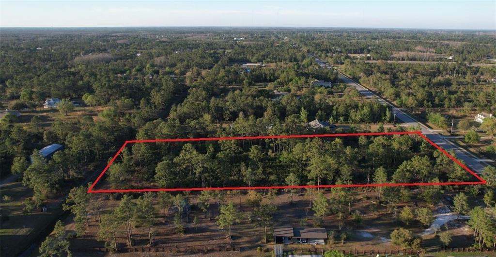 An aerial view shows a rectangular plot of land outlined in red amidst wooded surroundings — Lots 591-593 BANCROFT BOULEVARD, ORLANDO, FL