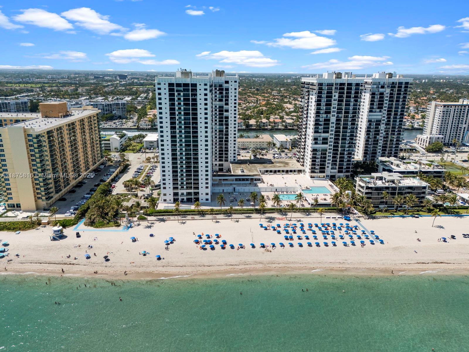 An aerial view shows high-rise residential buildings situated directly along a sandy beach — 2301 S Ocean Dr # 307, Hollywood FL 33019, HOLLYWOOD, FL