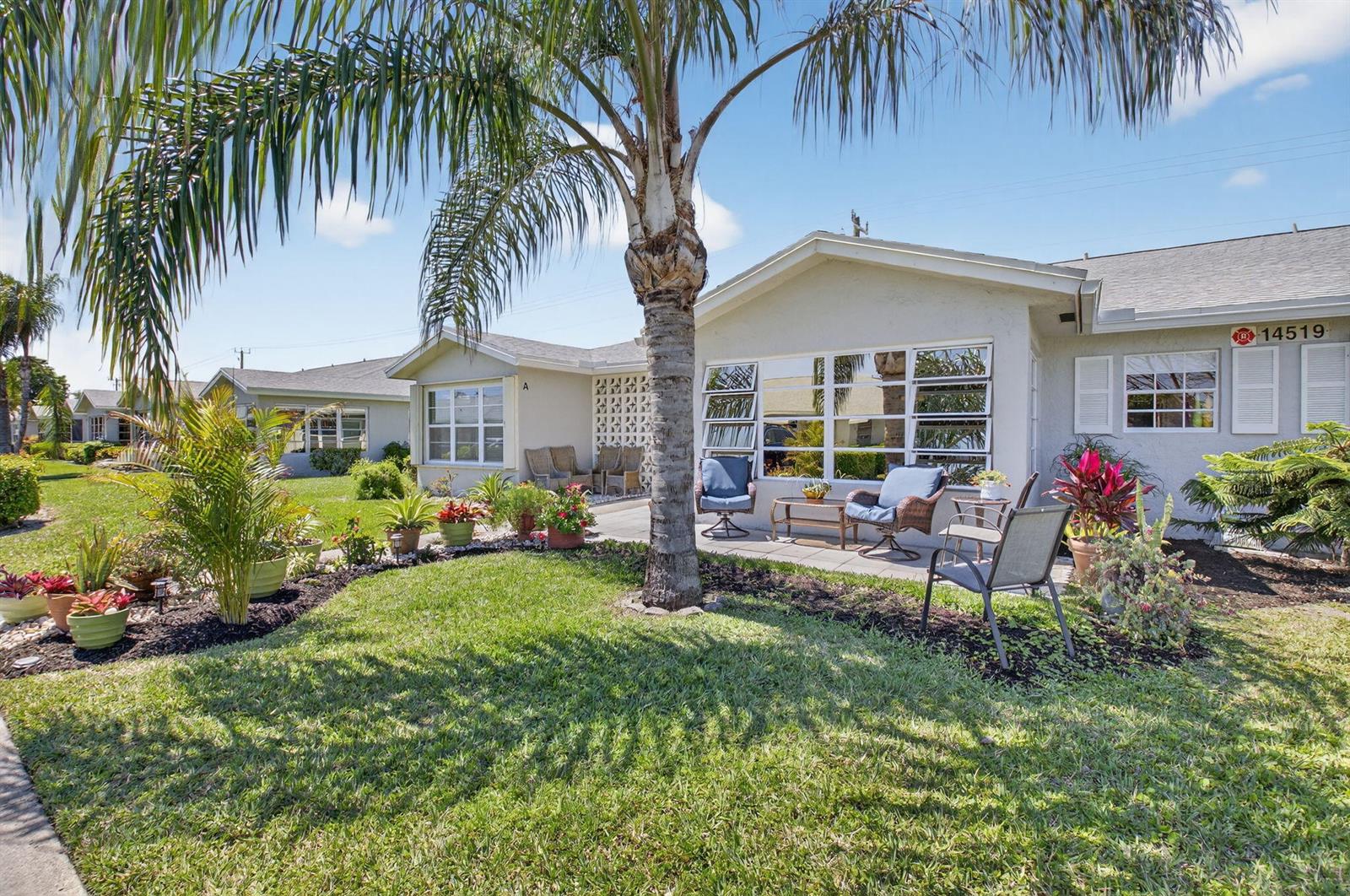 A palm tree stands in front of a single-story house with a patio and garden — 14519 Canalview Drive # B, Delray Beach FL 33484, DELRAY BEACH, FL
