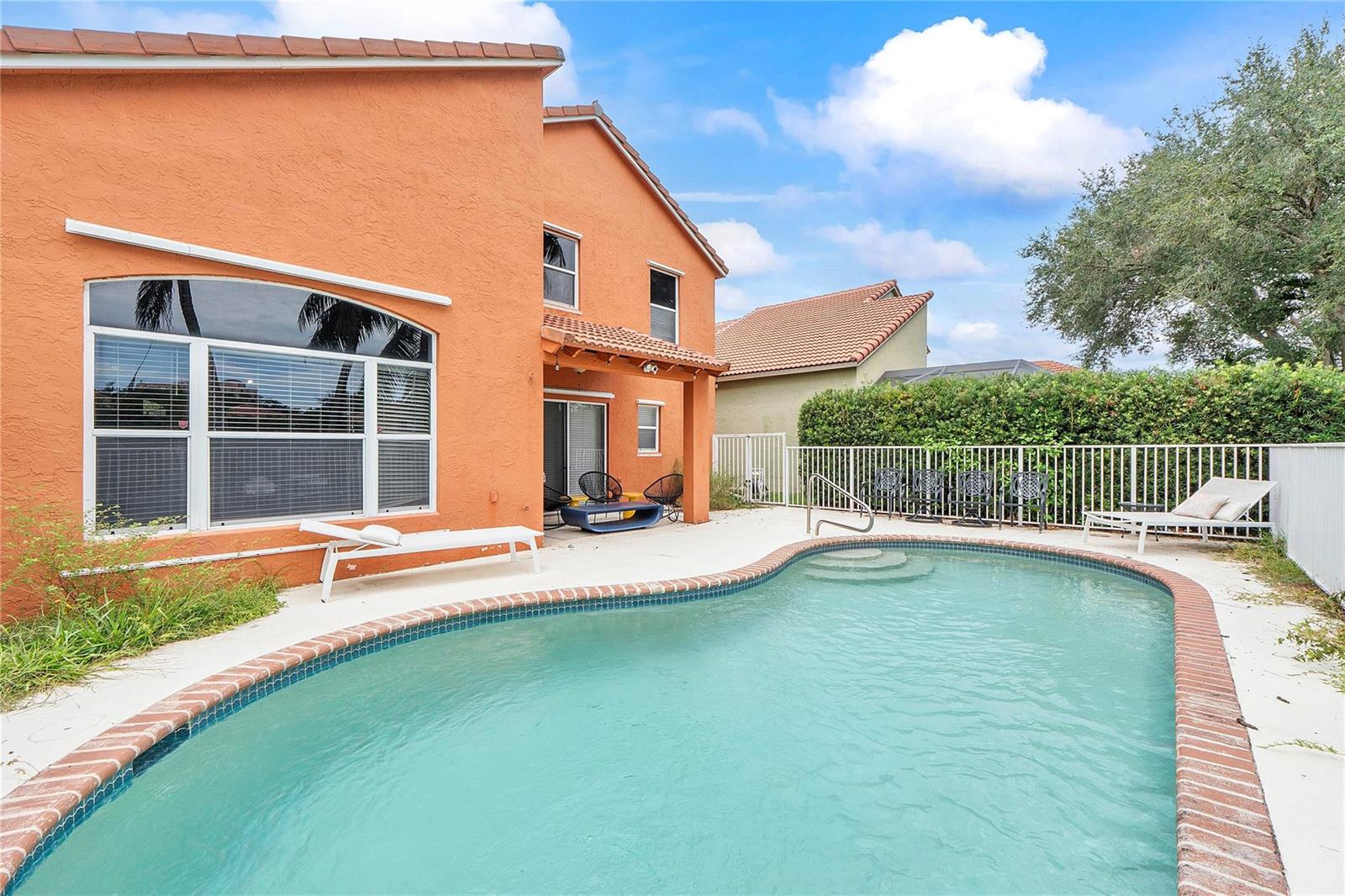 A two-story orange stucco house features a backyard swimming pool with a brick border — 4020 Dorado Drive, Riviera Beach FL 33418, RIVIERA BEACH, FL