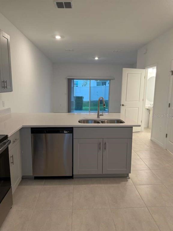 A kitchen features gray cabinets, a stainless steel dishwasher, and a sink on a white countertop — 3184 SKYLINE LOOP, POINCIANA, FL