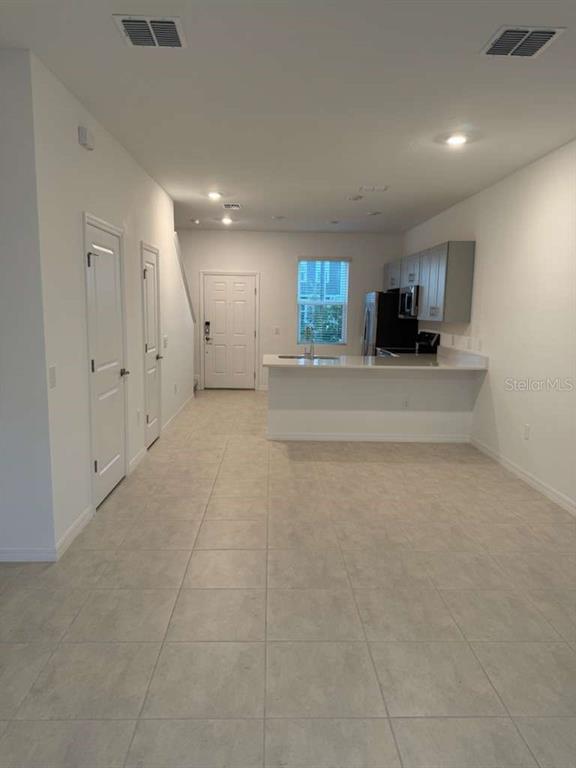 An open-concept kitchen and living area features light tile flooring and white cabinetry — 3184 SKYLINE LOOP, POINCIANA, FL