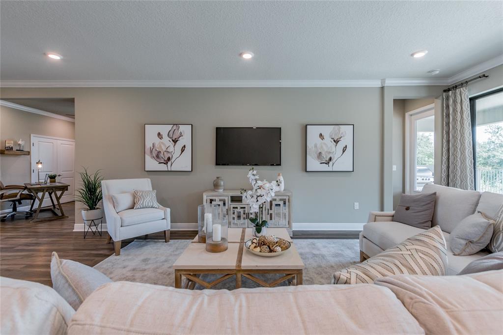 A living room features a wall-mounted television, a media console, and neutral-toned furniture — 704 ESTATES BOULEVARD, TARPON SPRINGS, FL