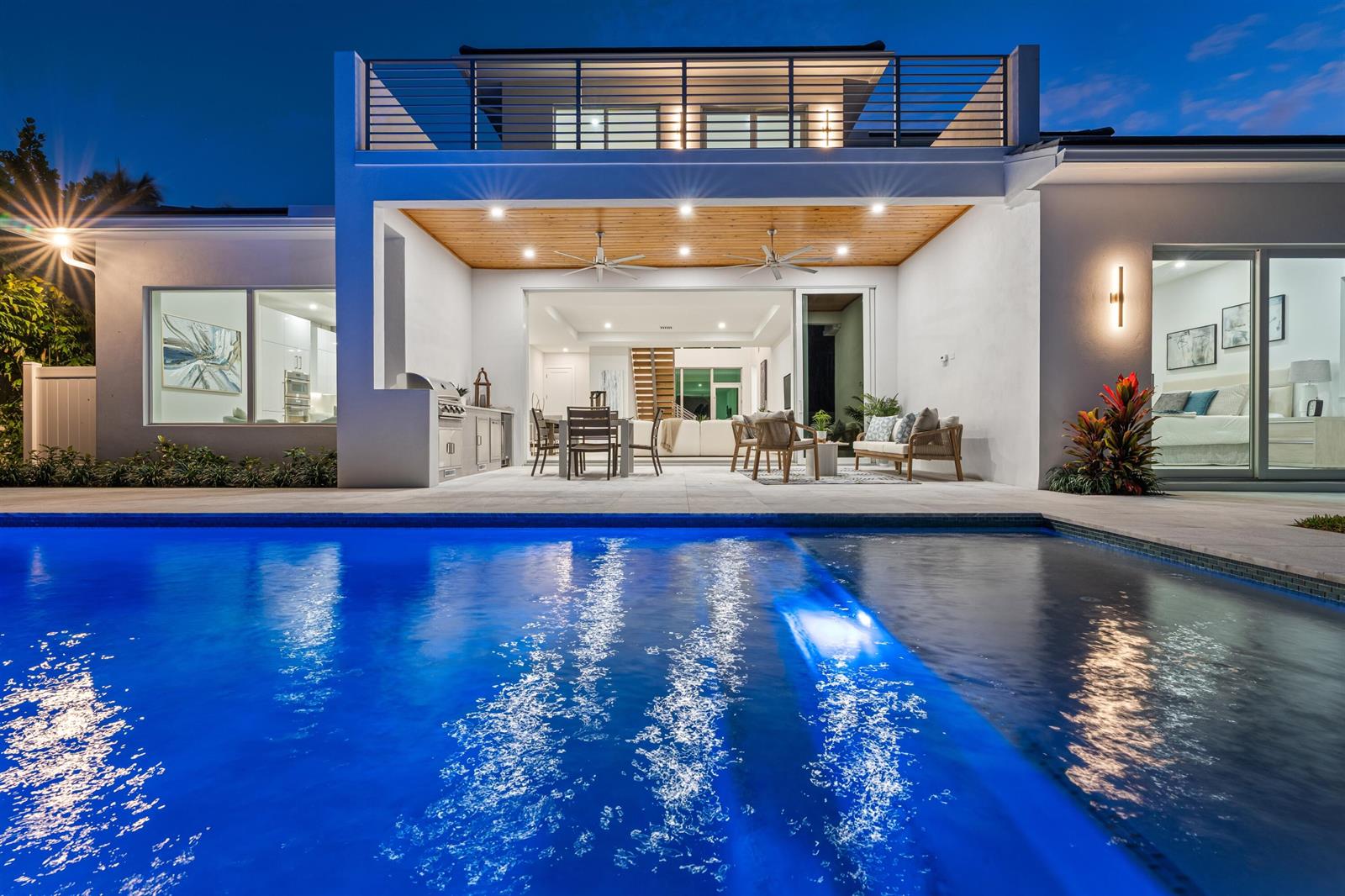 A modern house exterior at night featuring a swimming pool, covered patio, and balcony — 417 Lake Drive, Delray Beach FL 33444, DELRAY BEACH, FL