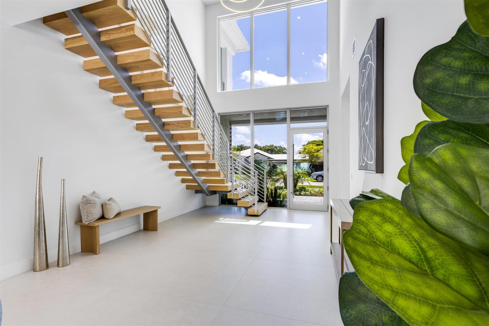 A bright entryway features a floating wooden staircase, white tile floors, and large glass windows — 417 Lake Drive, Delray Beach FL 33444, DELRAY BEACH, FL