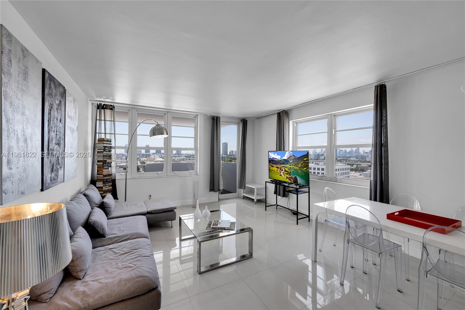 A bright living and dining area features white tile floors, modern furniture, and city views — 100 Lincoln Rd # 1511, Miami Beach FL 33139, MIAMI BEACH, FL