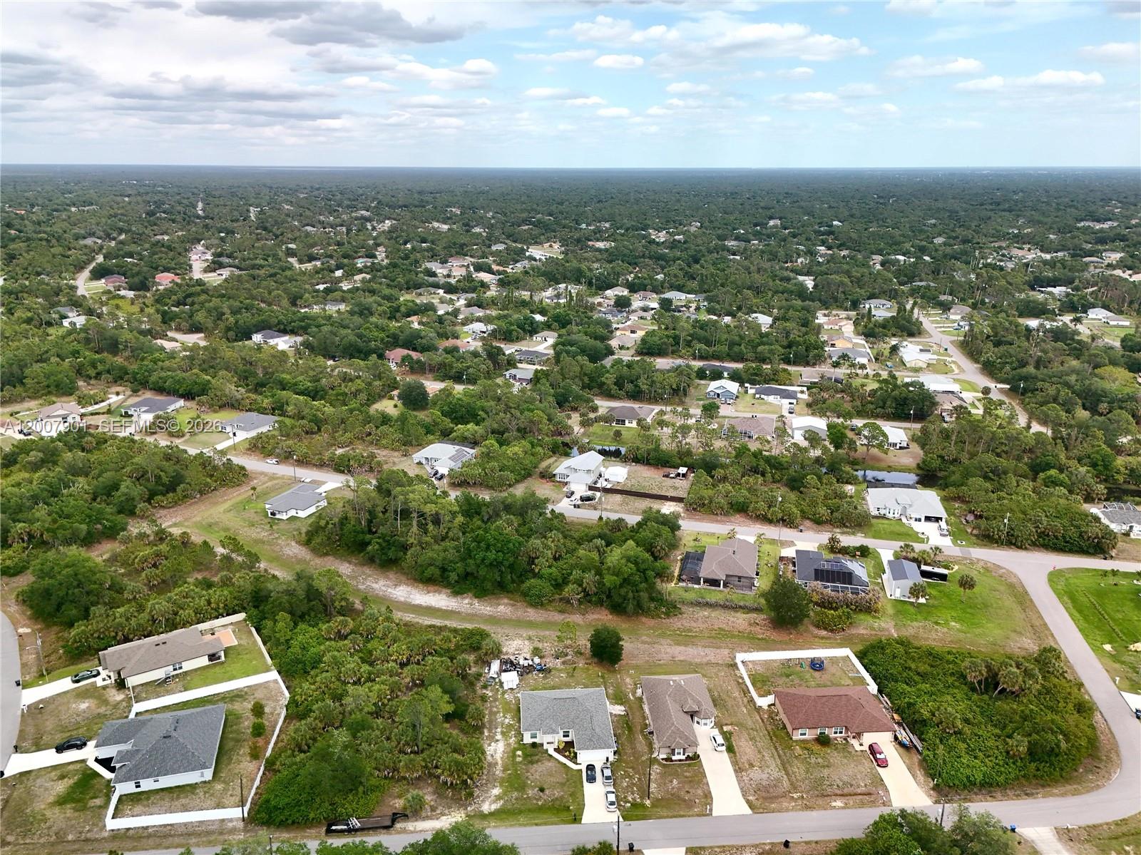 An aerial view shows a suburban neighborhood with scattered houses surrounded by dense green trees — 0 KISKA RD, North Port FL 34288, NORTH PORT, FL