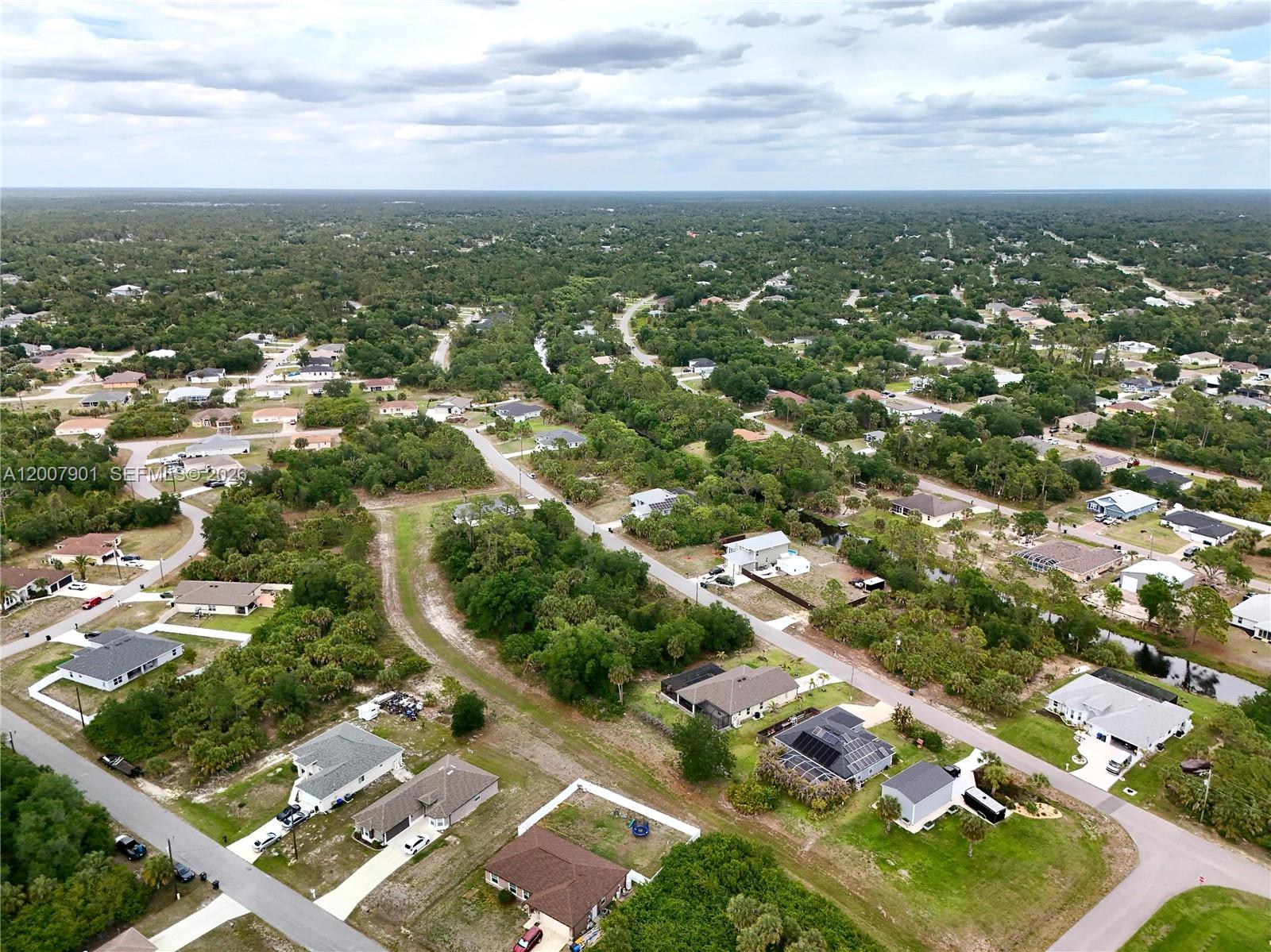 An aerial view shows a suburban neighborhood with houses, paved roads, and dense surrounding vegetation — 0 KISKA RD, North Port FL 34288, NORTH PORT, FL