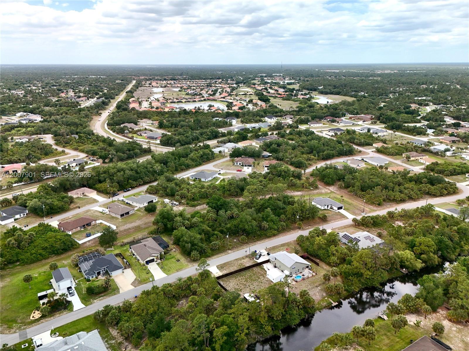 An aerial view shows a residential neighborhood with scattered houses, wooded areas, and a canal — 0 KISKA RD, North Port FL 34288, NORTH PORT, FL