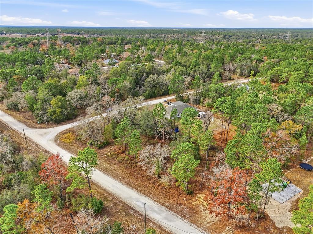 An aerial view shows a house situated on a wooded lot near a dirt road — 16364 CAYMAN ROAD, BROOKSVILLE, FL