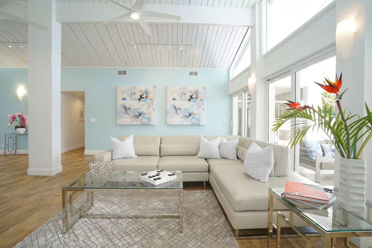 A bright living room features a cream sectional sofa, glass coffee table, and light blue walls — 1000 NE 8th Street, Pompano Beach FL 33060, POMPANO BEACH, FL