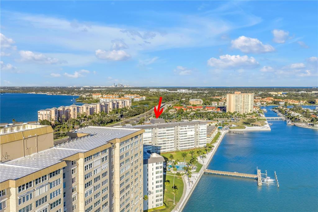 An aerial view shows multiple high-rise apartment buildings situated along a waterfront with a pier — 5108 BRITTANY DRIVE S UNIT 204, ST PETERSBURG, FL