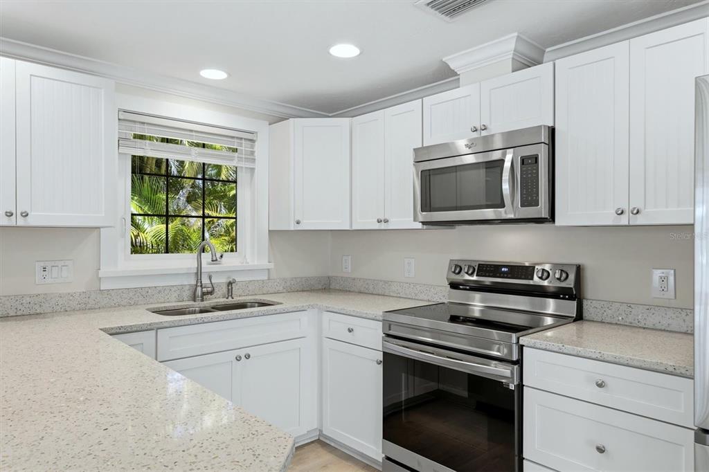 A kitchen with white cabinets, stainless steel appliances, and speckled light-colored countertops — 5803 DE PALMAS AVENUE, HOLMES BEACH, FL