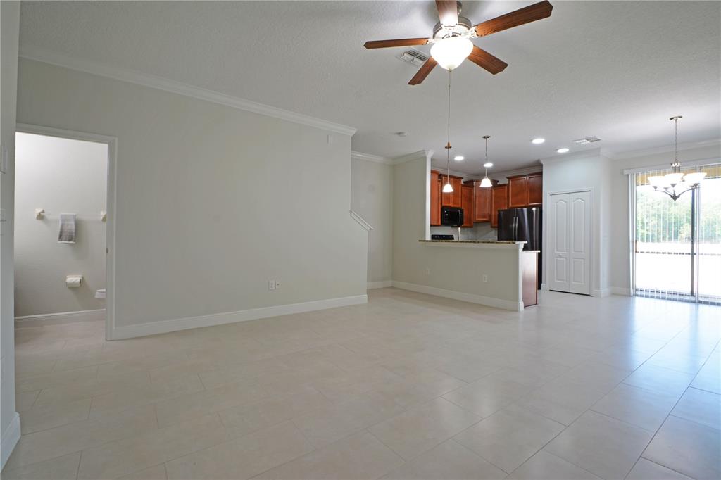 An open-concept living area features tile flooring, a kitchen with wood cabinets, and a bathroom — 11925 GREENGATE DRIVE, HUDSON, FL