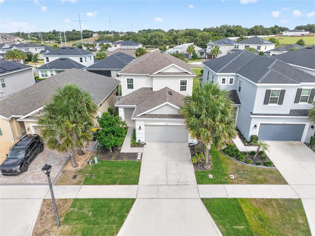 An aerial view shows a two-story suburban house with a concrete driveway and palm trees — 2722 SURF TOP ROAD, CLERMONT, FL