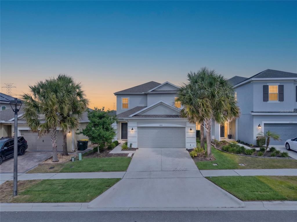 A two-story suburban house with a gray exterior, two-car garage, and palm trees in front — 2722 SURF TOP ROAD, CLERMONT, FL