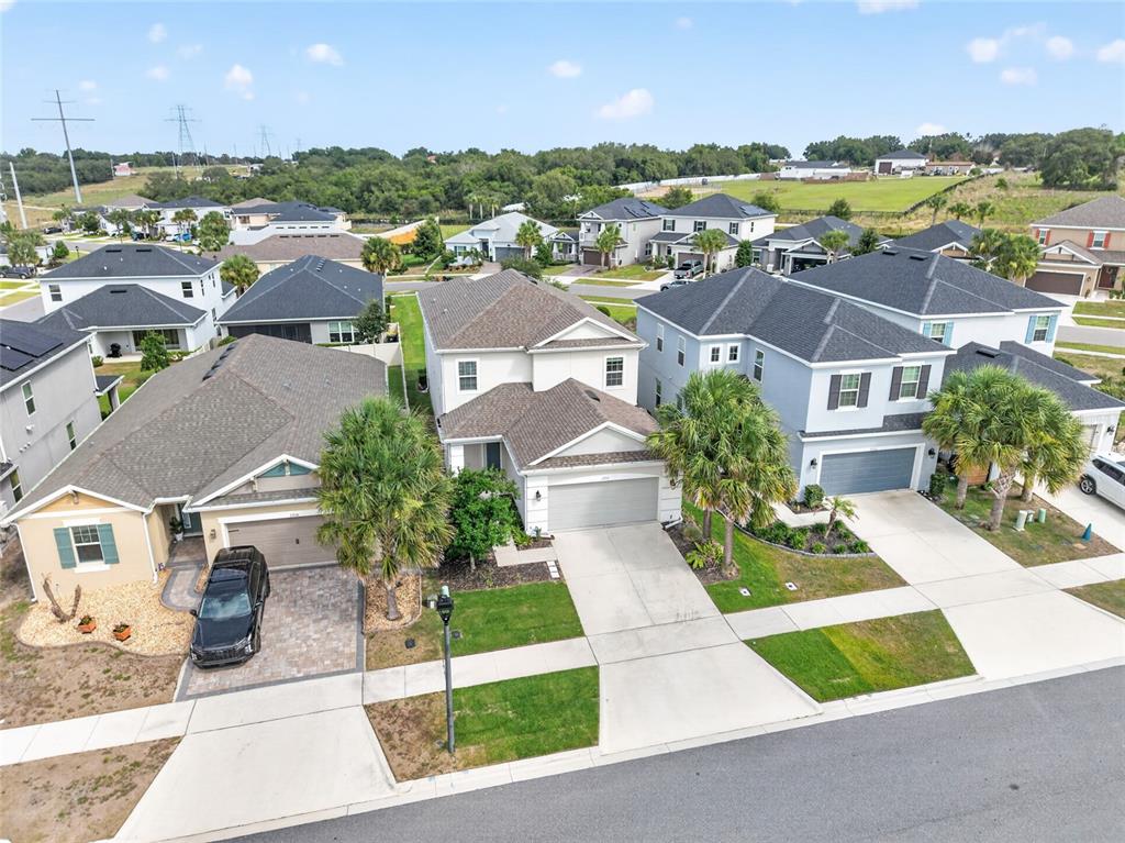 An aerial view shows three suburban houses with driveways and palm trees on a sunny day — 2722 SURF TOP ROAD, CLERMONT, FL