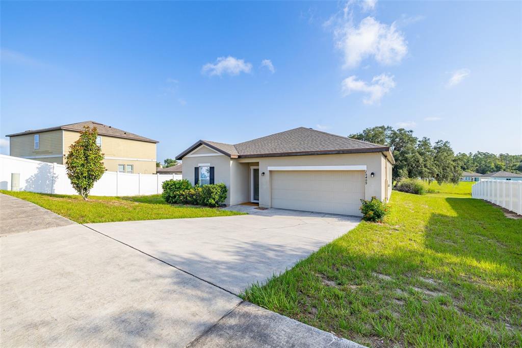 A single-story house with a beige exterior, a two-car garage, and a concrete driveway — 15409 IVORY GULL LANE, MASCOTTE, FL