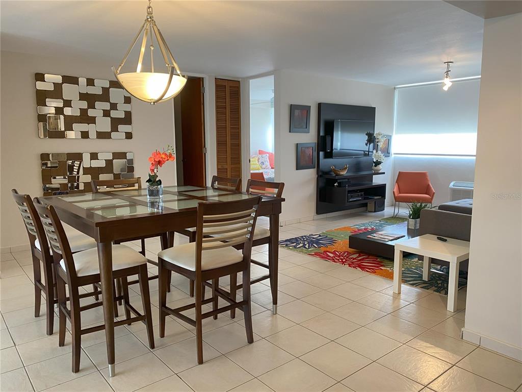 A dining area with a glass-top table and a living room with a colorful rug — 1020 DIAZ WAY STREET UNIT 720, CAROLINA, PR