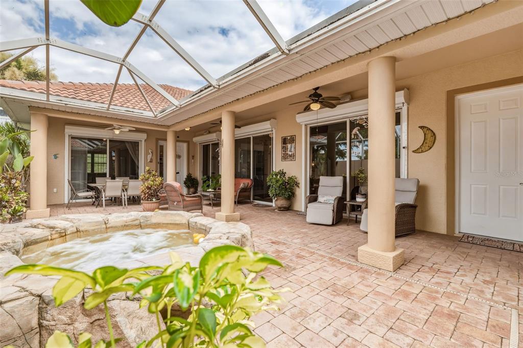 A screened-in patio features a stone hot tub, brick pavers, and multiple seating areas — 13921 BENTLY CIRCLE, FORT MYERS, FL