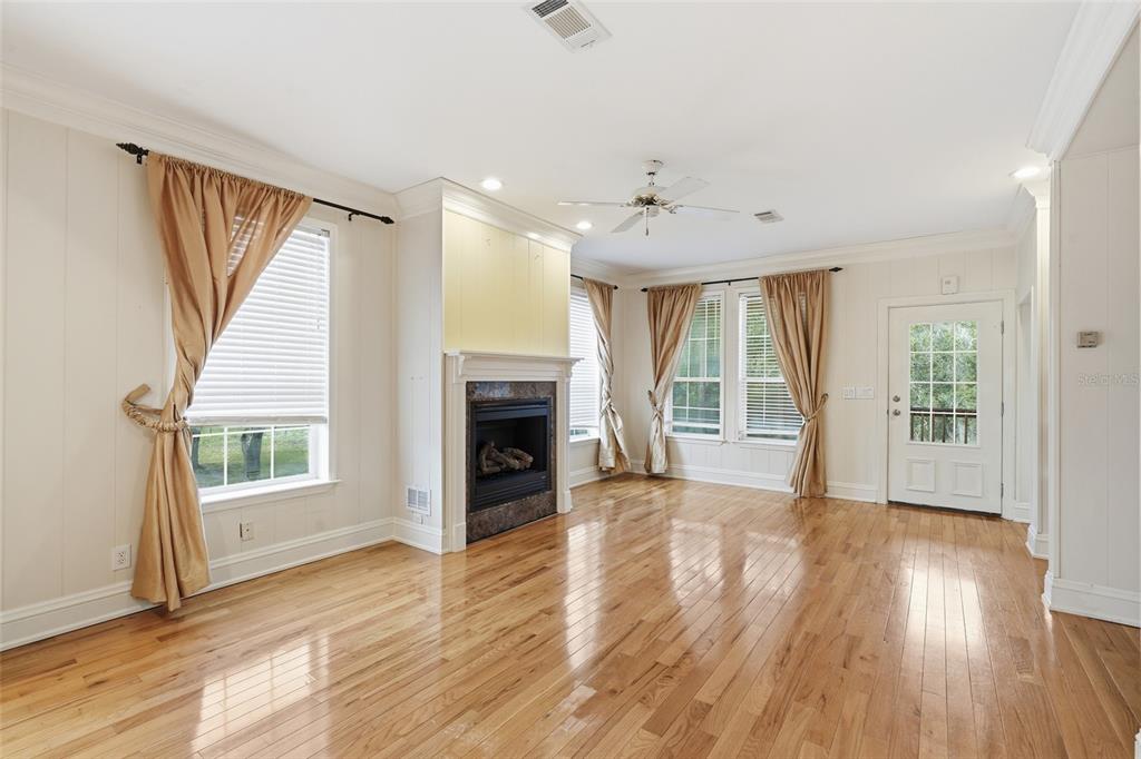 A living room features hardwood floors, a fireplace, large windows with curtains, and a door — 11604 SE SHELFER AVENUE, ARCADIA, FL